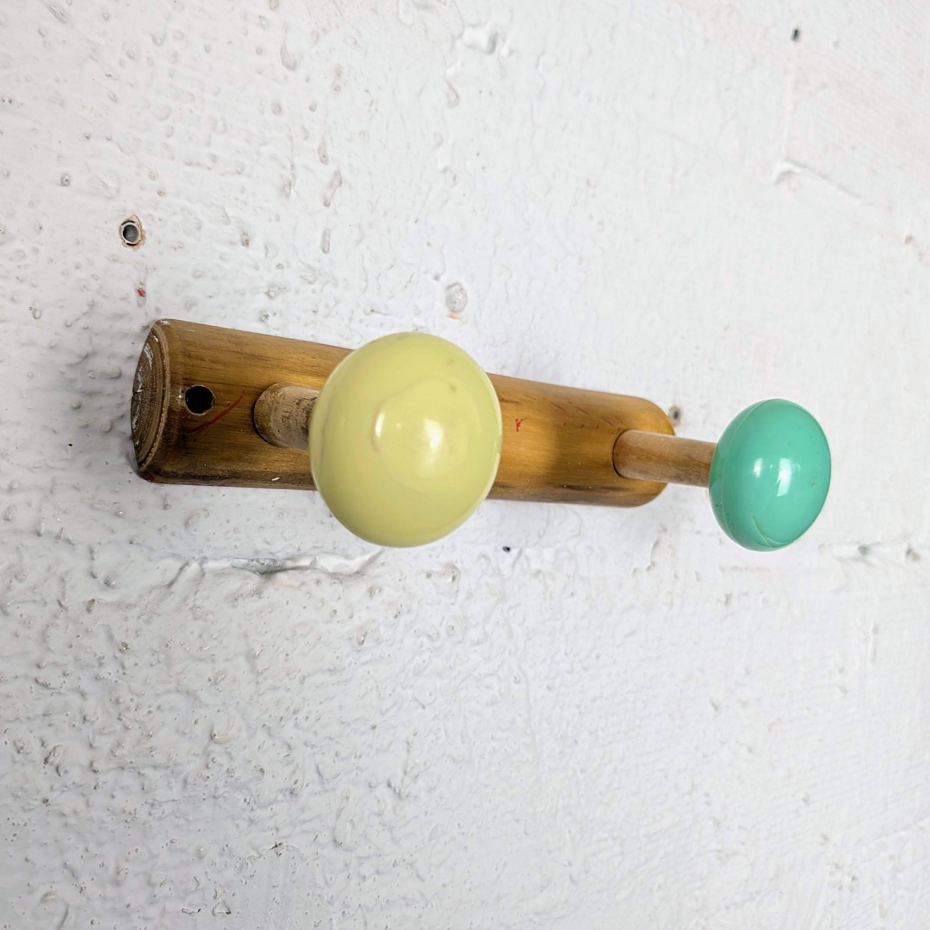 Vintage wall coat rack with 2 yellow and green balls.