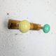 Vintage wall coat rack with 2 yellow and green balls.