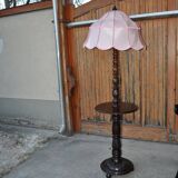Brown carved wooden floor lamp with a pale pink shade and integrated shelf.