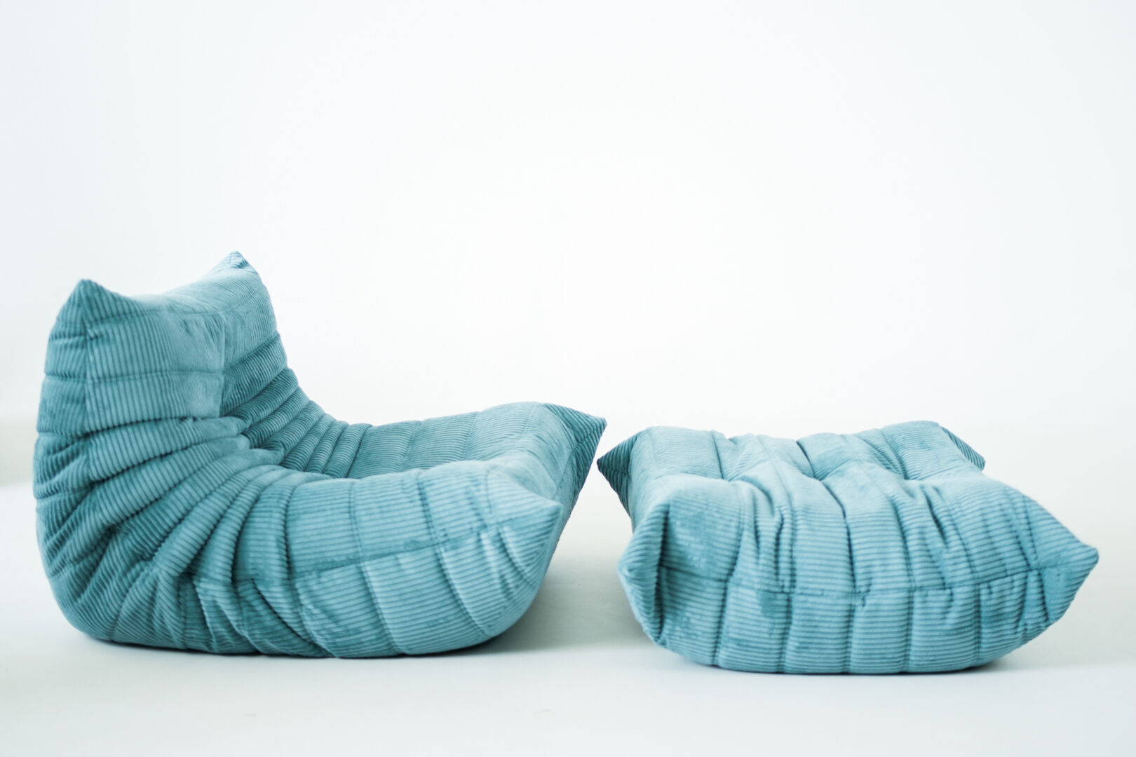 Ensemble de fauteuil et pouf Togo en velours côtelé bleu clair.