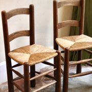 Pair of wooden chairs with woven straw seats.