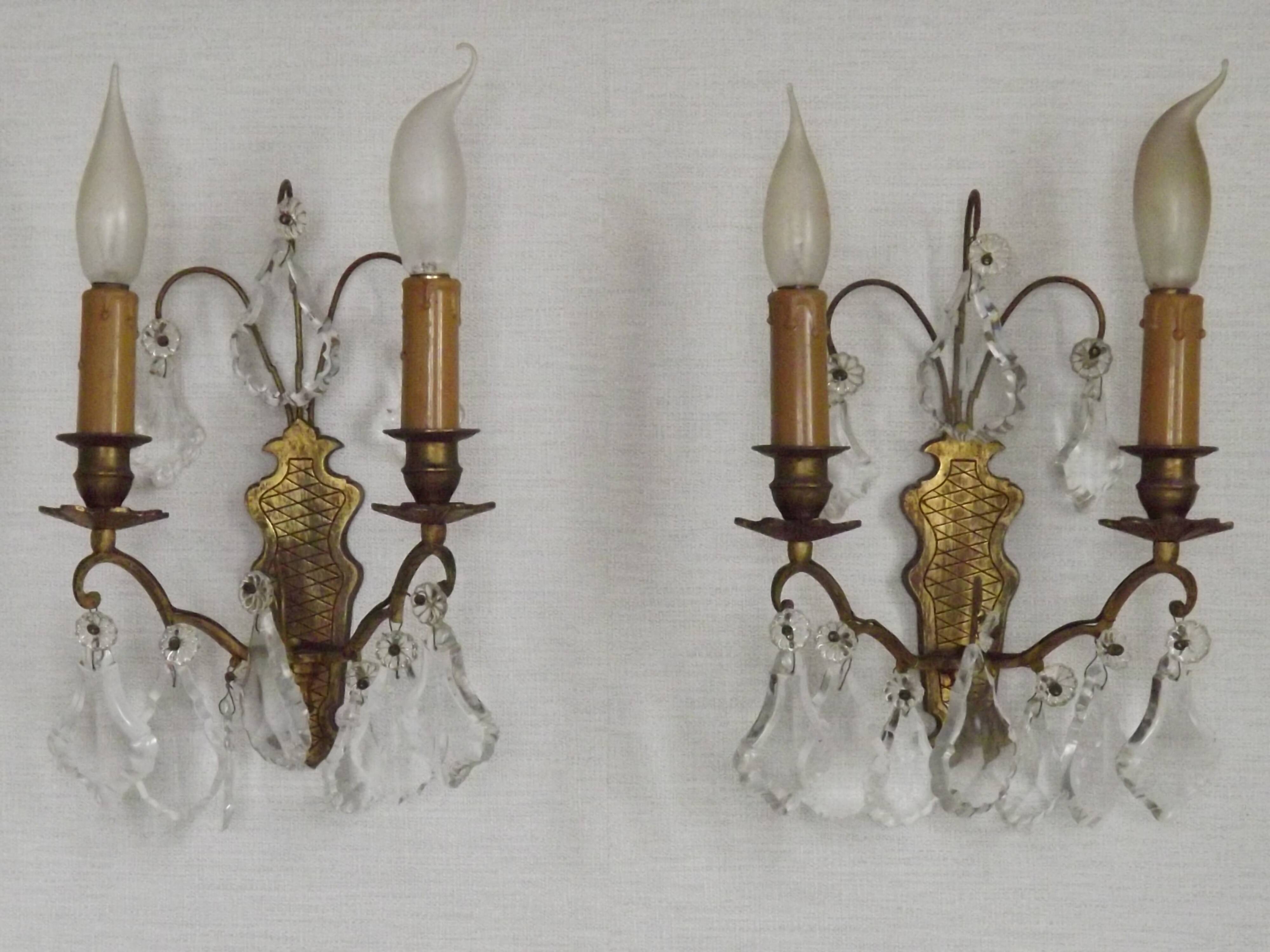 Pair of French antique brass double wall lights with assorted crystals.