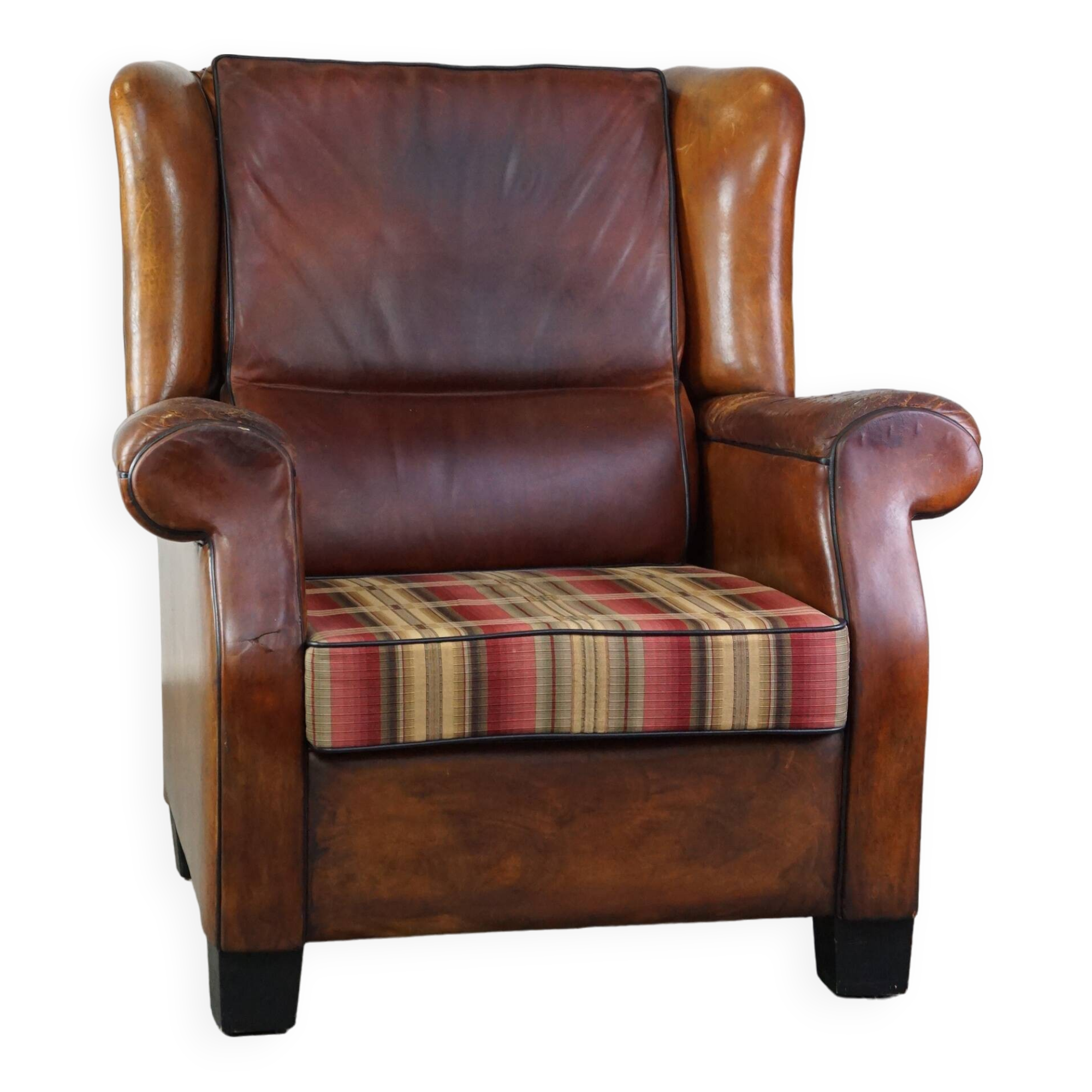 Very large worn sheepskin wing chair with a checked seat cushion