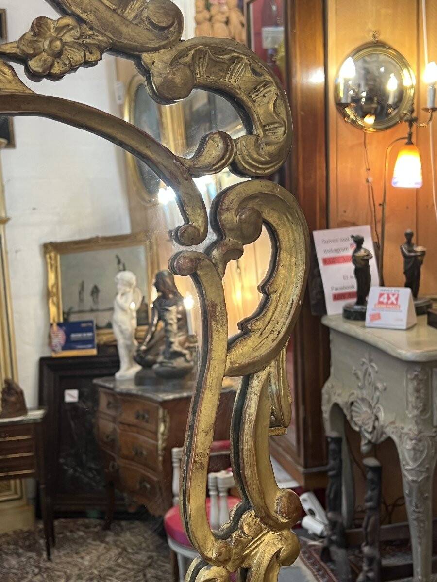 Mirror with carved and gilded wooden frame, 18th century, with scrollwork decoration.