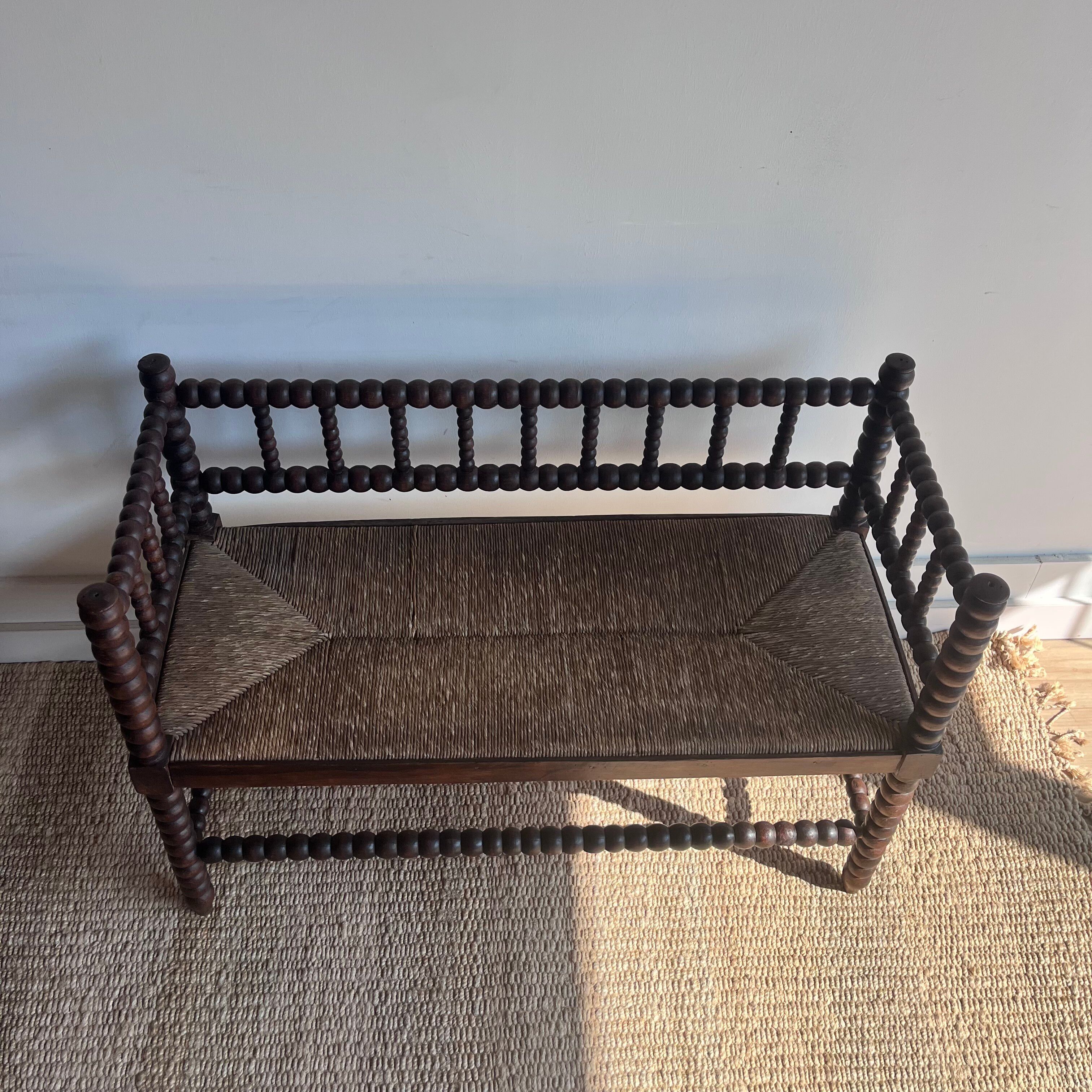Turned wood bobbin bench with a straw seat.