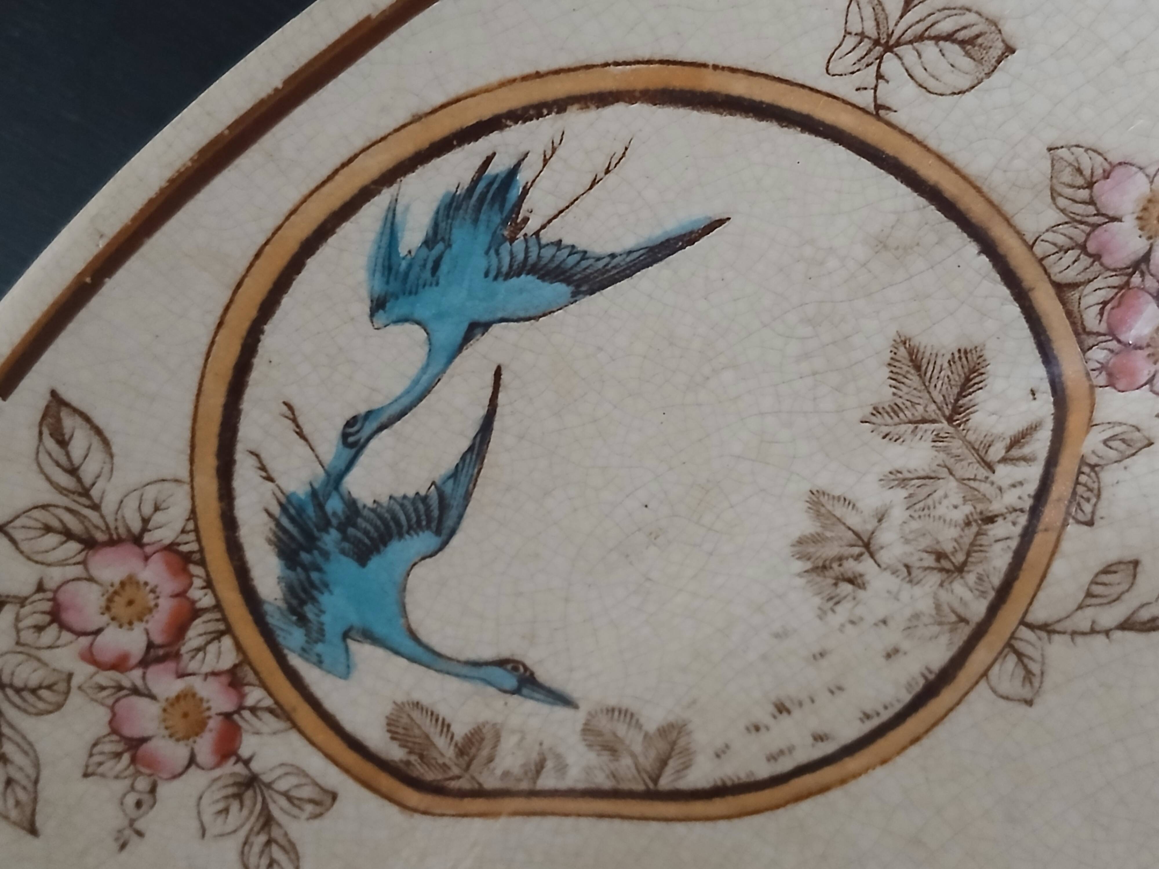 Large antique plate stamped with a fauna and flora pattern.