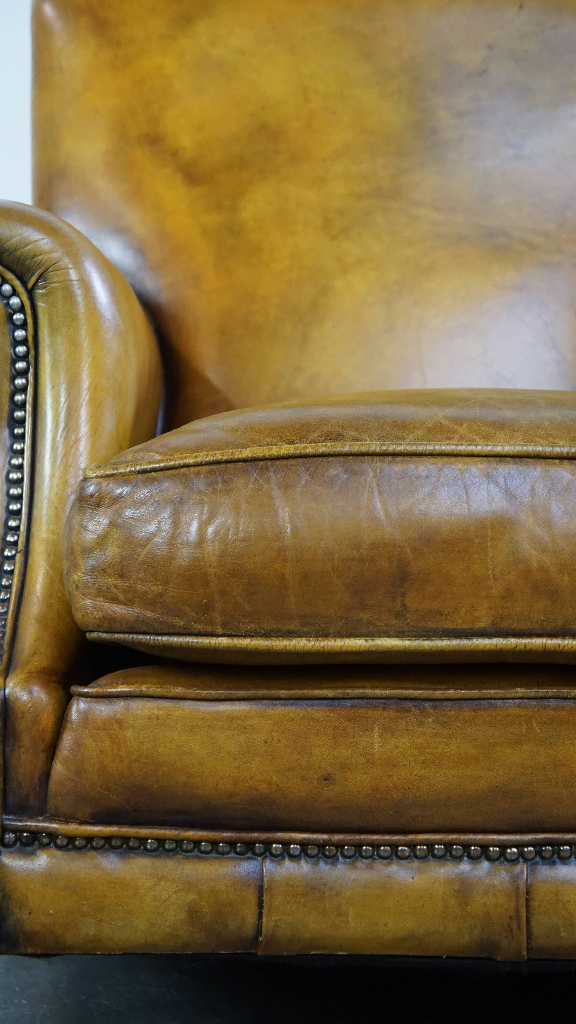 Comfortable large yellow English-style leather armchair with a fine finish and decorative nails