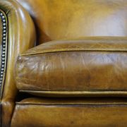 Comfortable large yellow English-style leather armchair with a fine finish and decorative nails