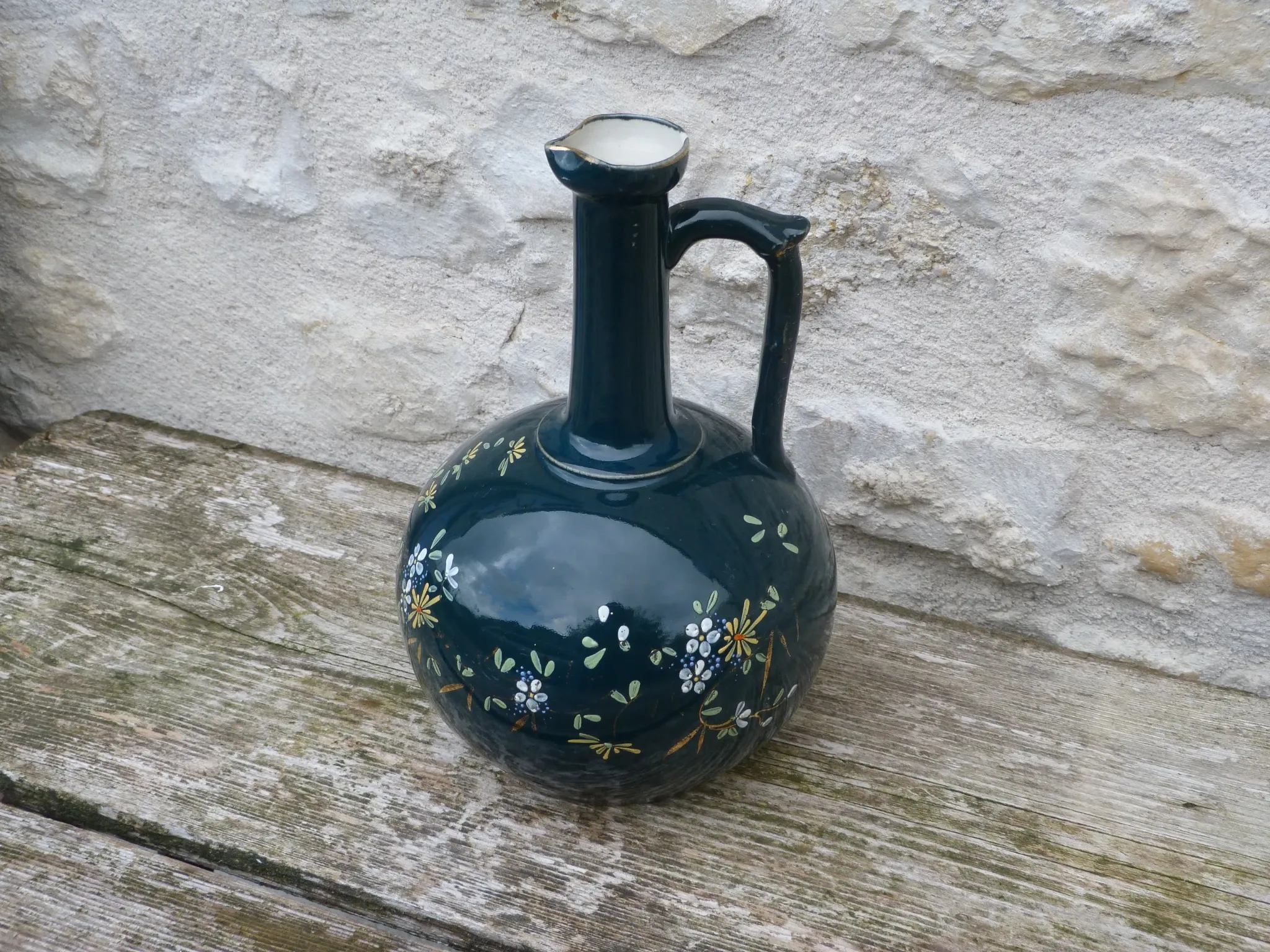 Old ceramic jug with flowers or single-stem vase.