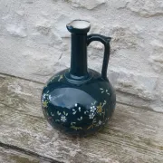 Old ceramic jug with flowers or single-stem vase.