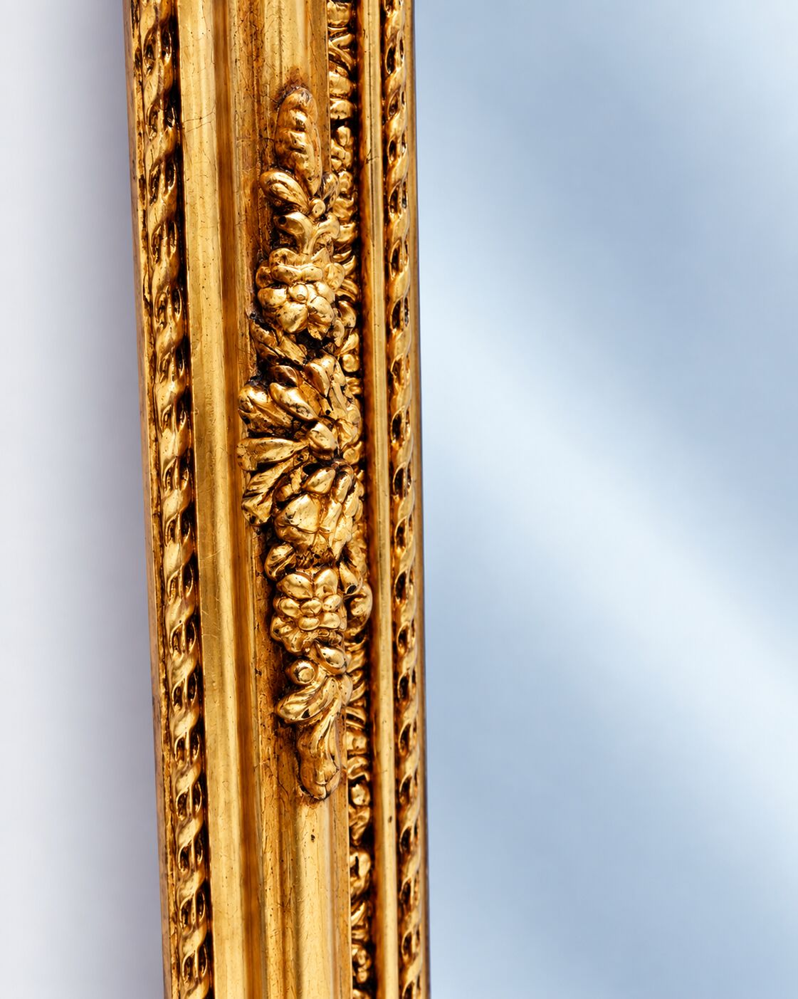Grand miroir baroque en or avec un crête orné.