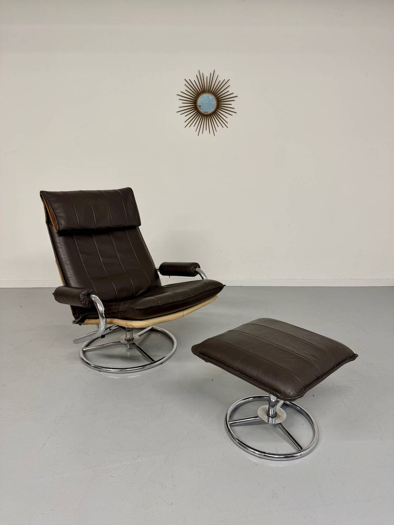 Vintage leather reclining armchair and its 1970s designer ottoman.