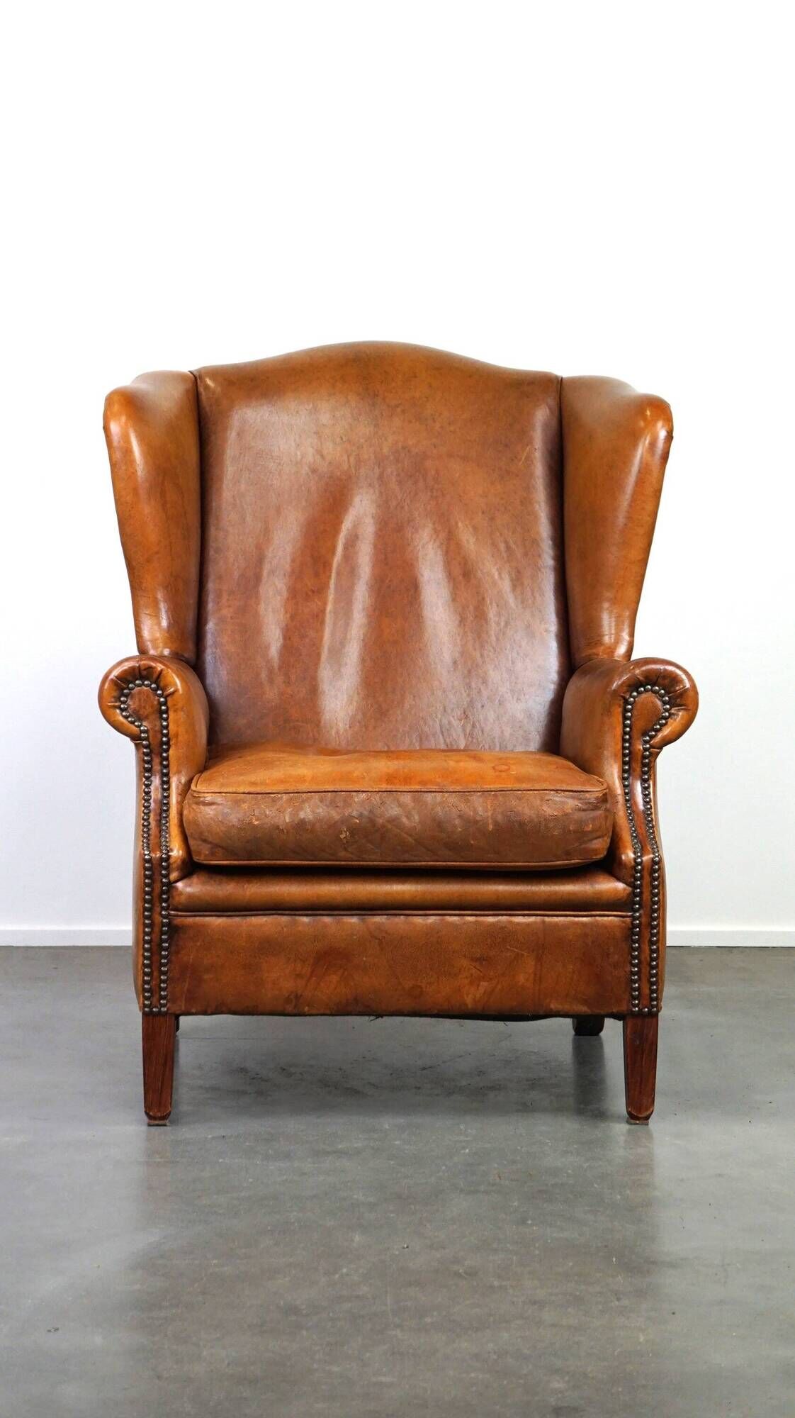 Positively lived-in sheepskin leather wing chair with pleasant seating comfort