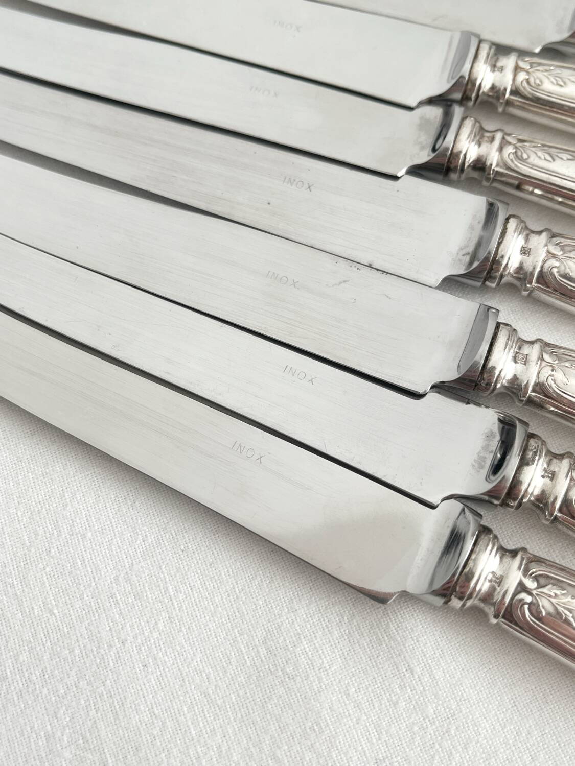 12 antique silver-plated knives with acanthus shell decoration and stainless steel blades.