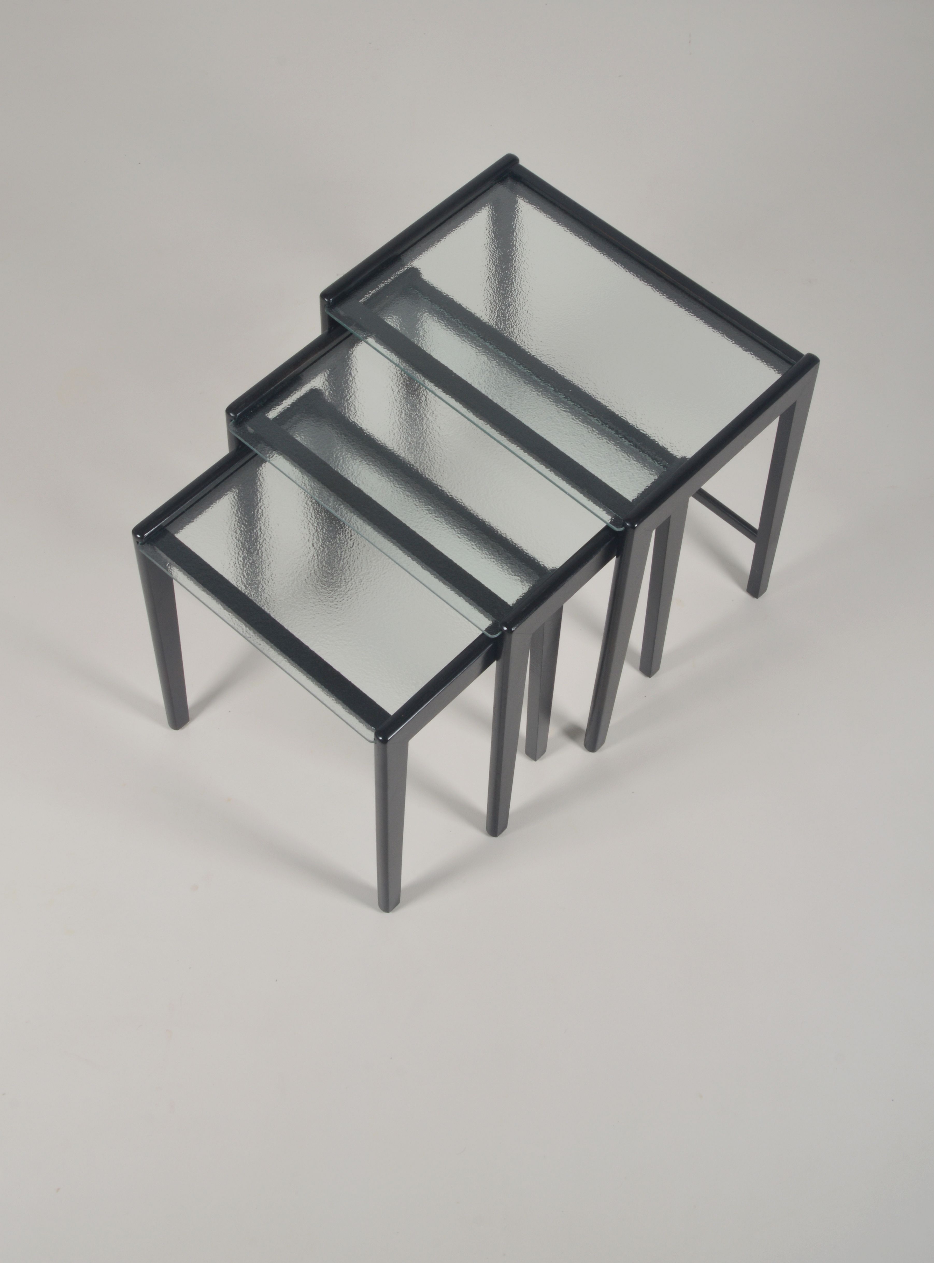 Tables gigognes en bois teinté noir et plateau en verre, années 1960