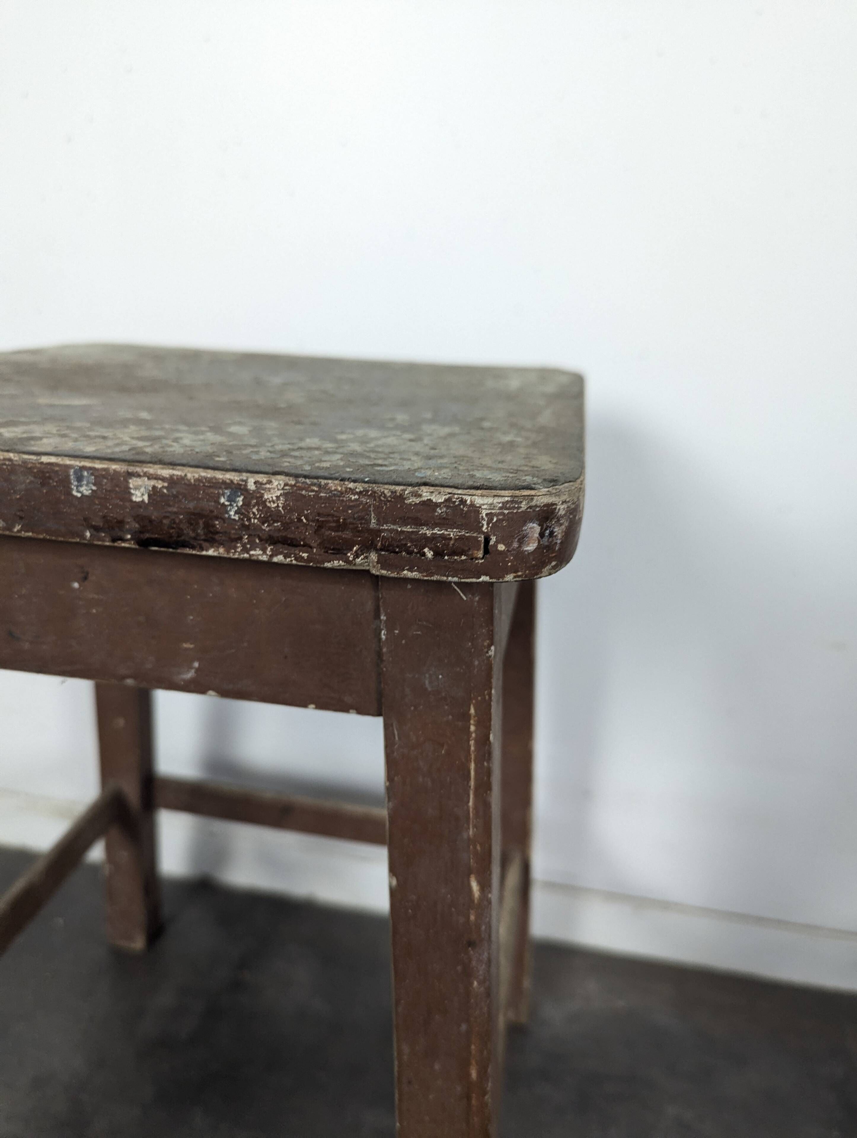 Brown painted wooden workshop stool with a patinated top.