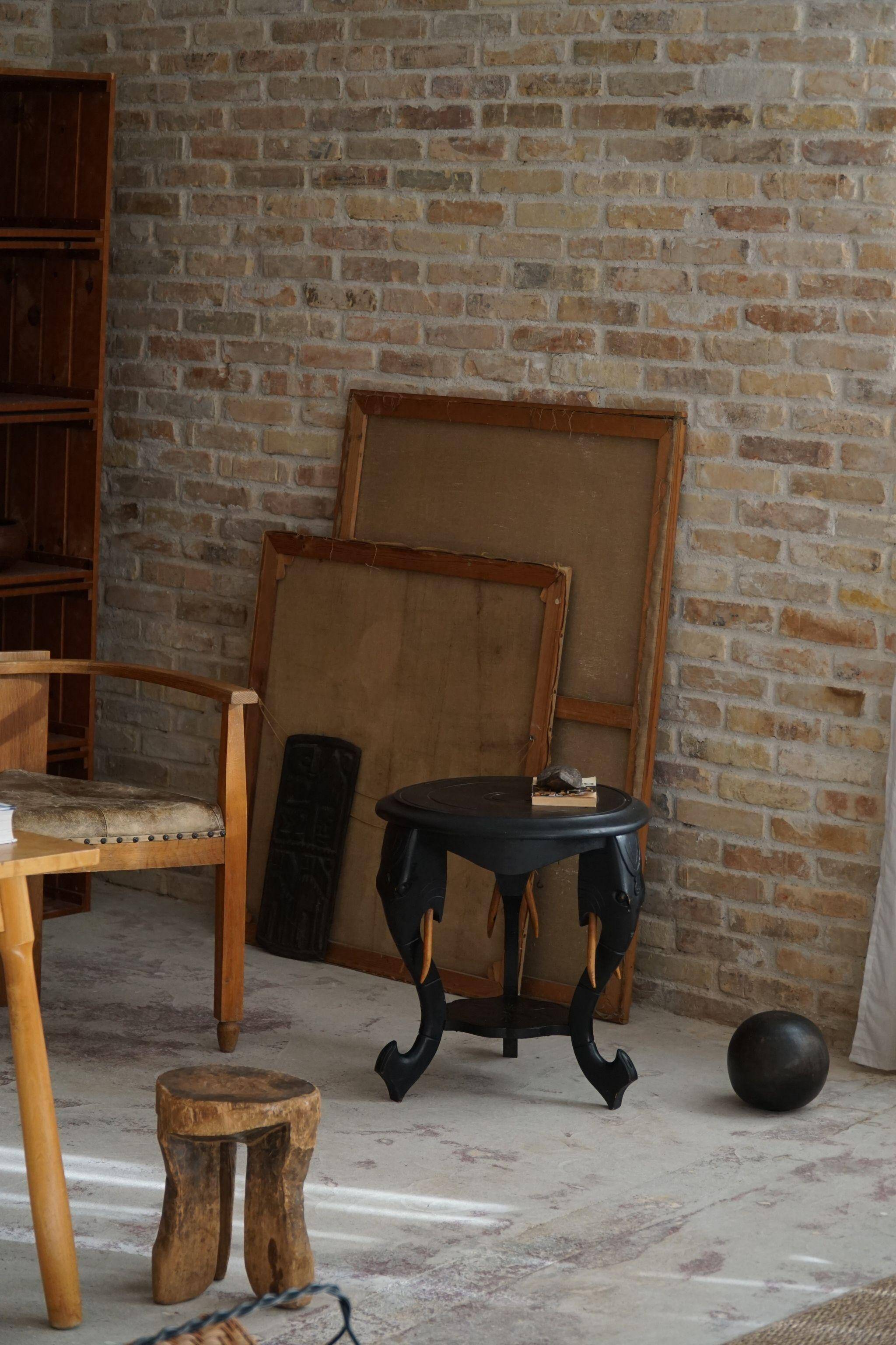 Side table in hardwood ebony with three elephant head-shaped legs, Eastern India, 1920s.