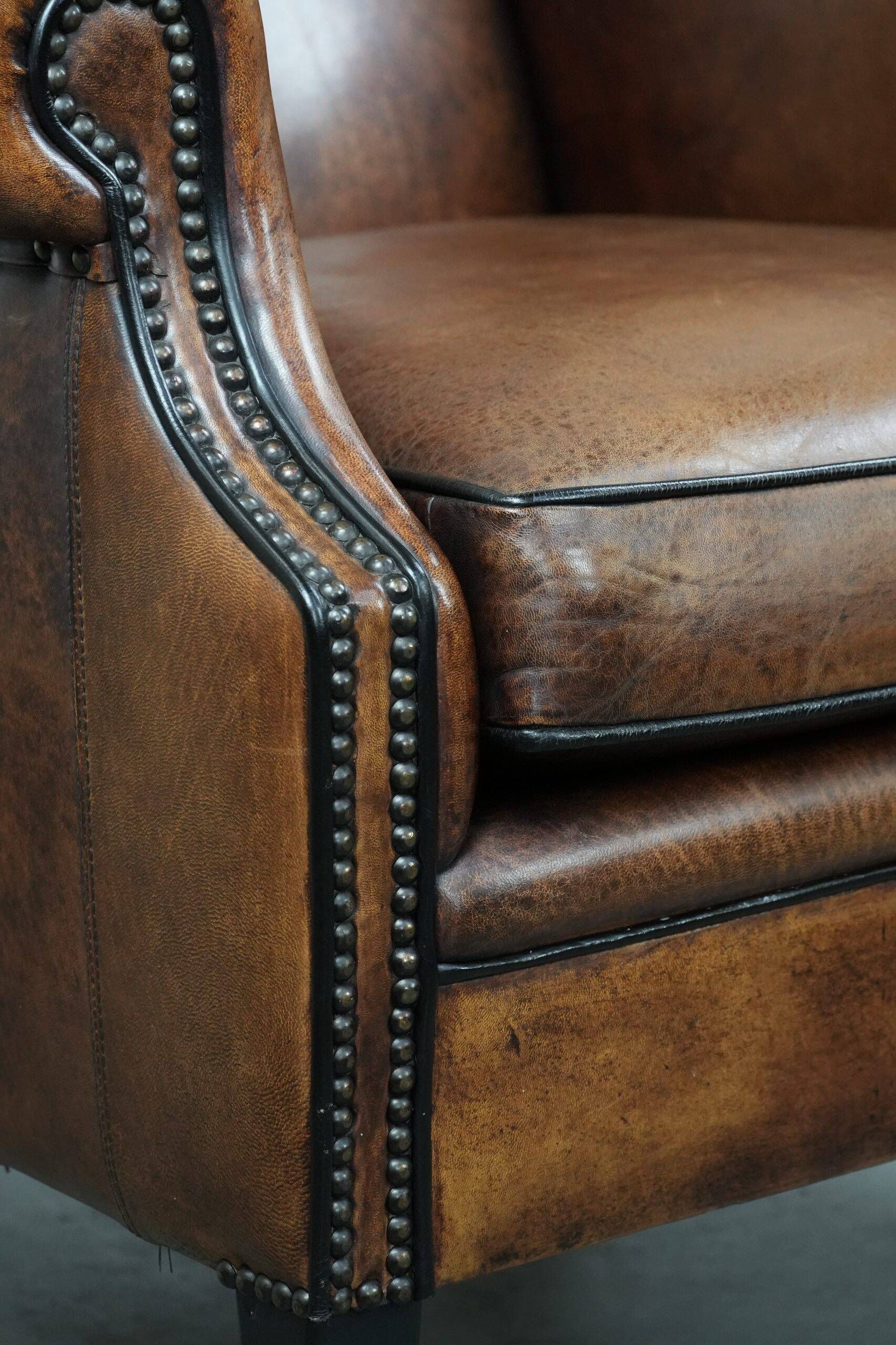 Sheepskin wingback armchair with decorative nails and black piping