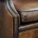 Sheepskin wingback armchair with decorative nails and black piping