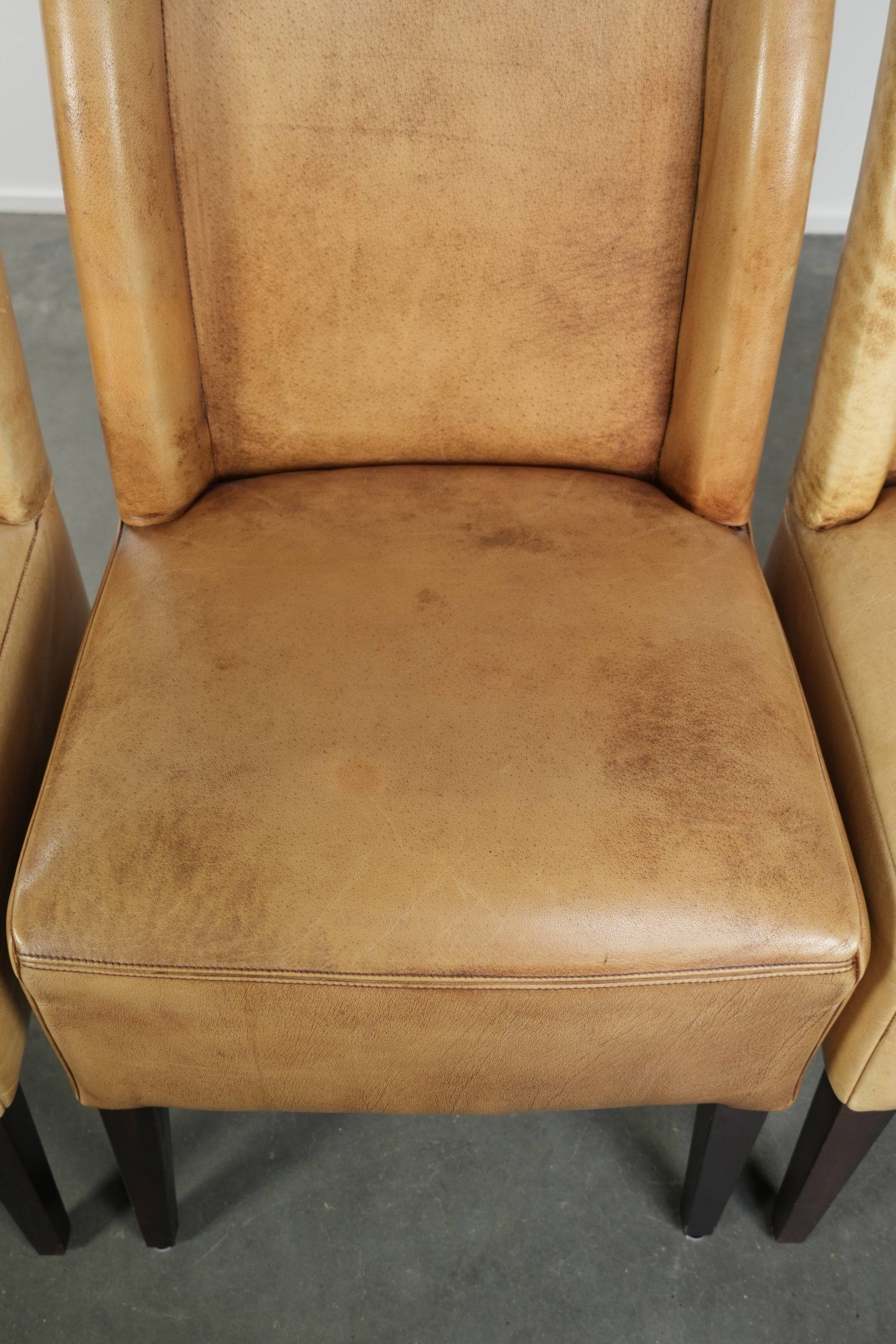 Ensemble de quatre chaises de salle à manger en cuir de vache avec un siège confortable et un dossier haut.