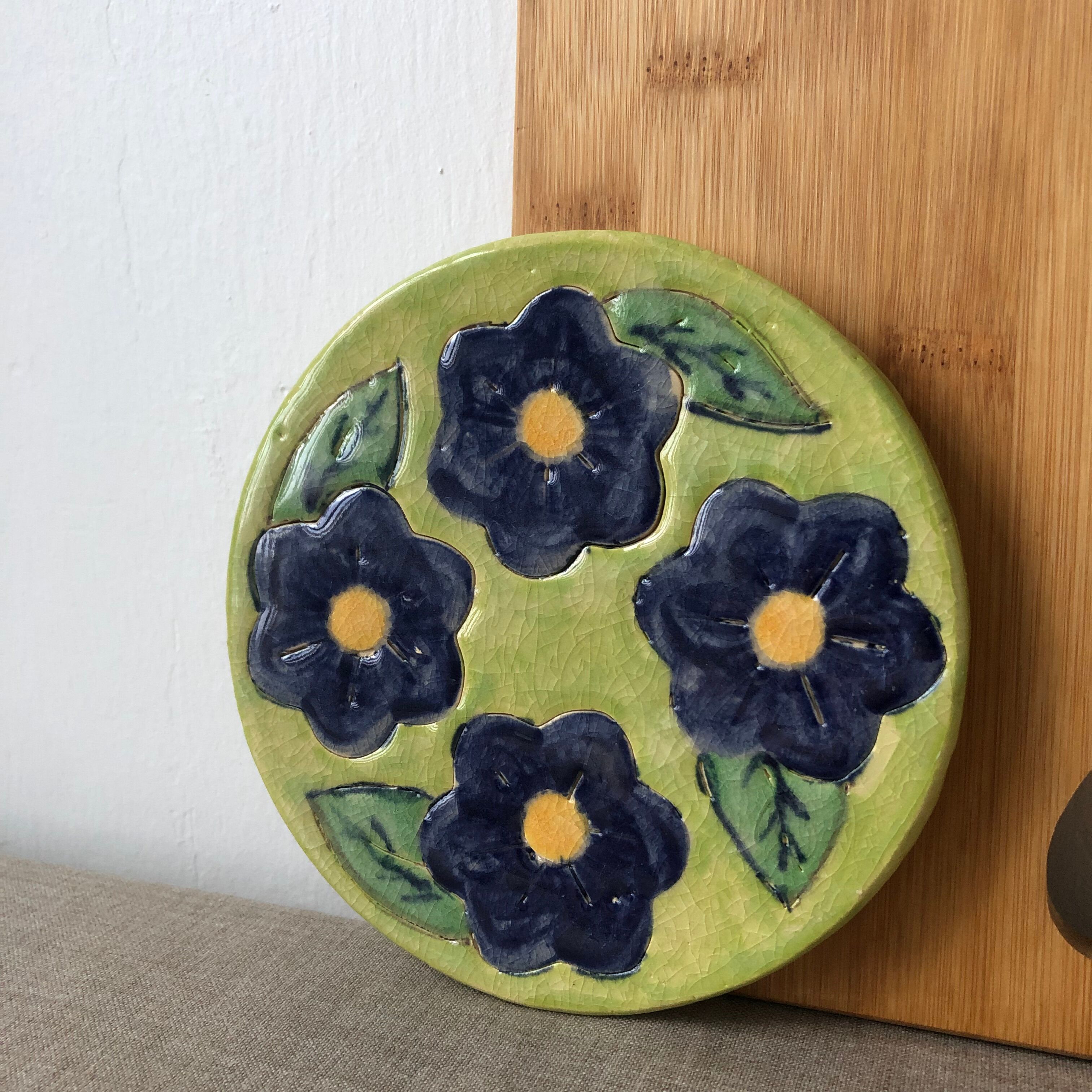 Round trivia decorated with blue flowers on a green background.
