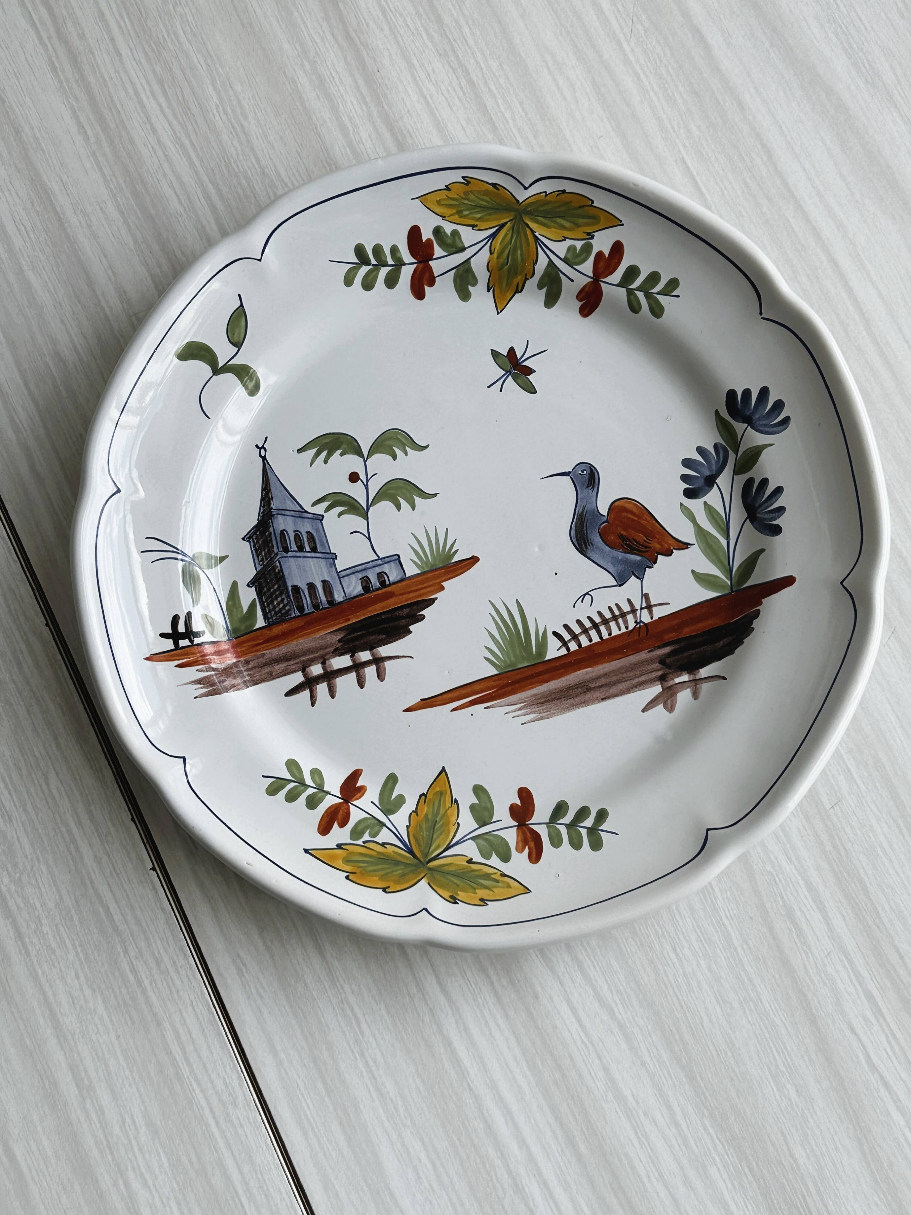 Hand-painted earthenware plate with landscape and bird decoration.