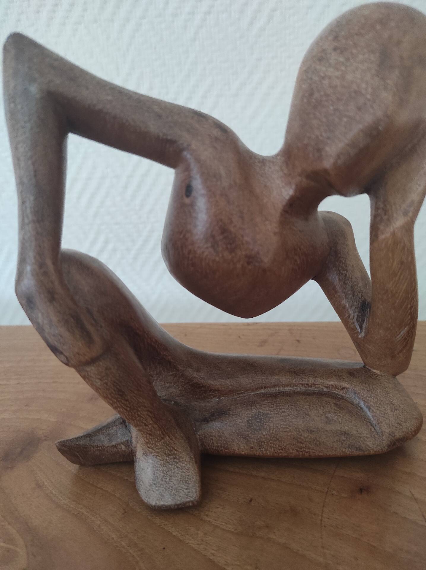 Wooden sculpted statuette of a woman in a pensive pose.