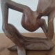 Wooden sculpted statuette of a woman in a pensive pose.