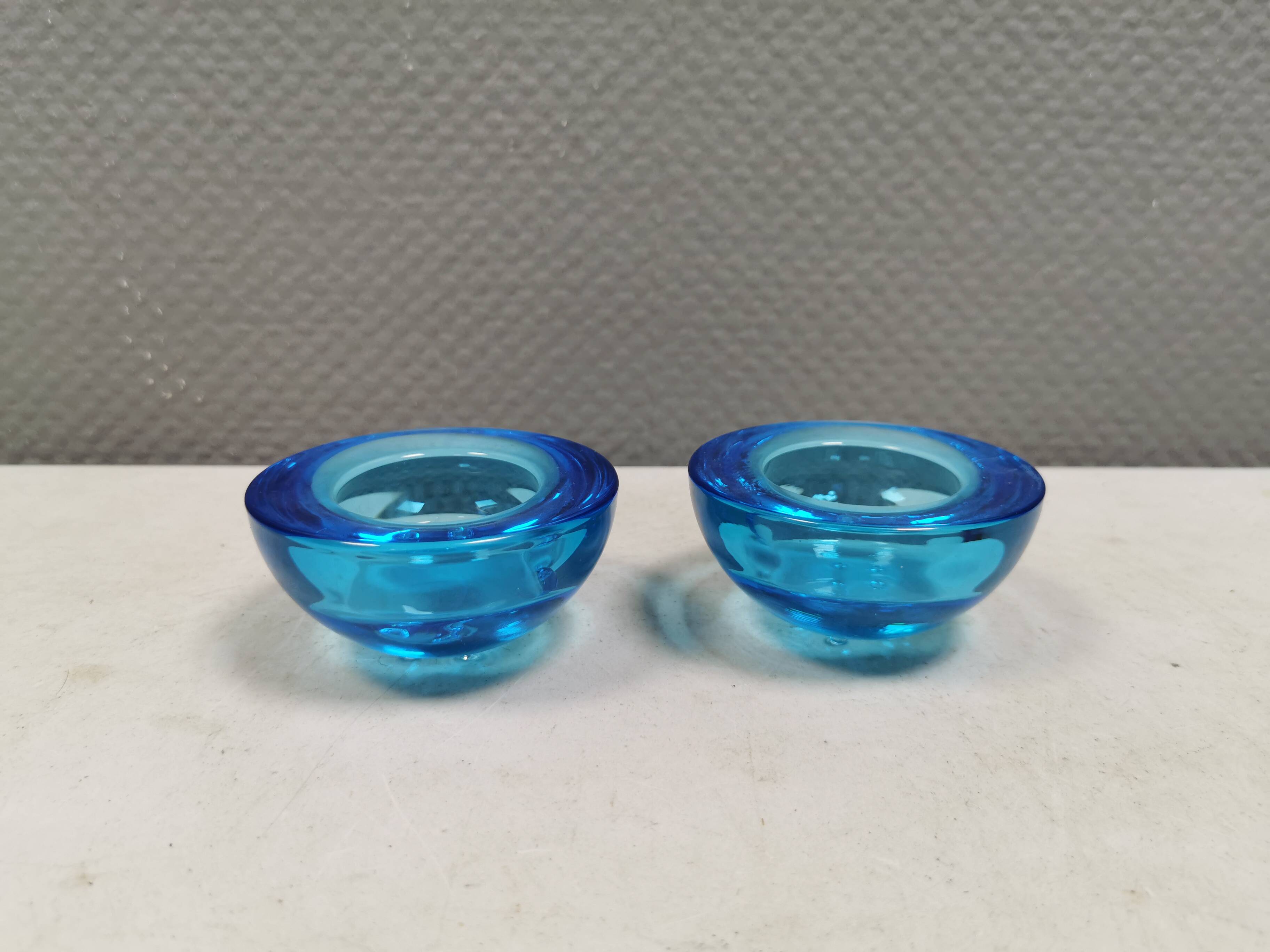 A set of iitalla candle holders in blue transparent glass.