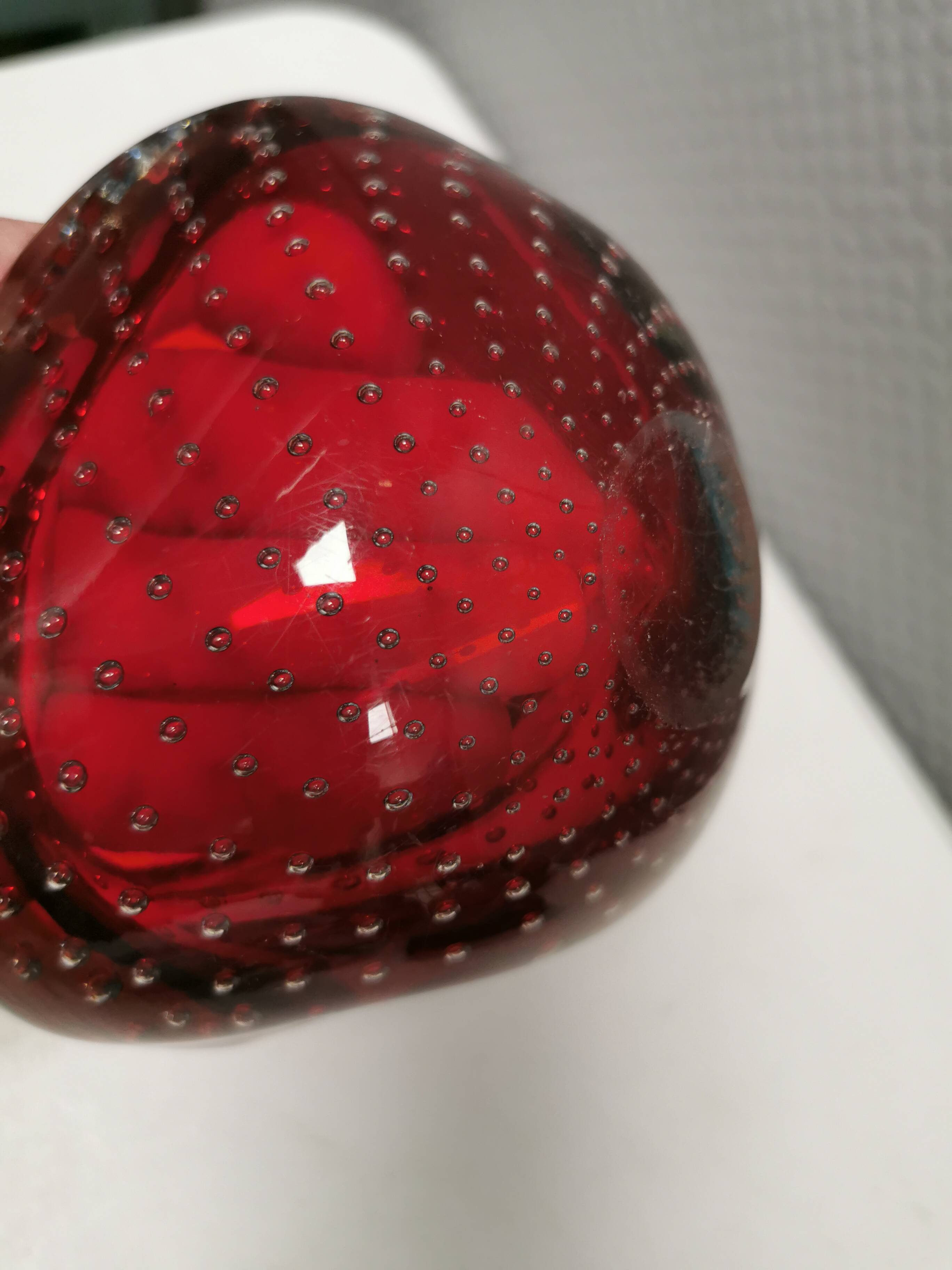 Small glass bowl in beautiful emerald red color with inlaid bubbles.