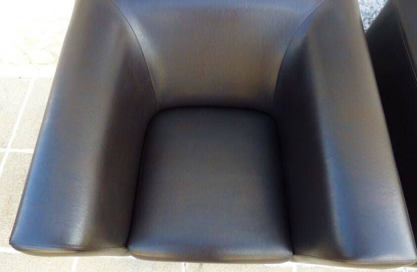 2 club armchairs with a chocolate faux leather seat and backrest and wooden legs.