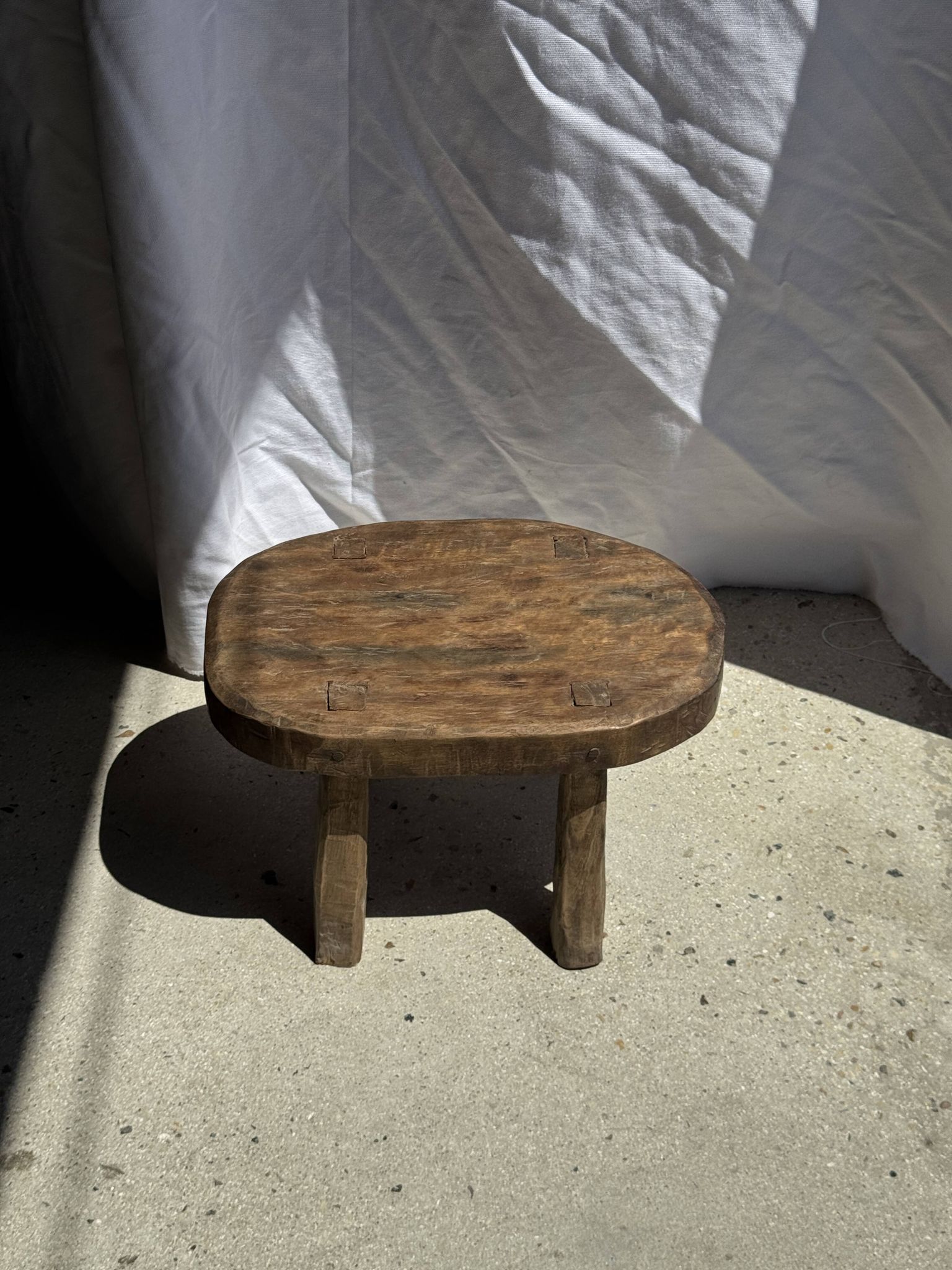 Small stool, oval solid teak side table with curved legs in wabi-sabi style.