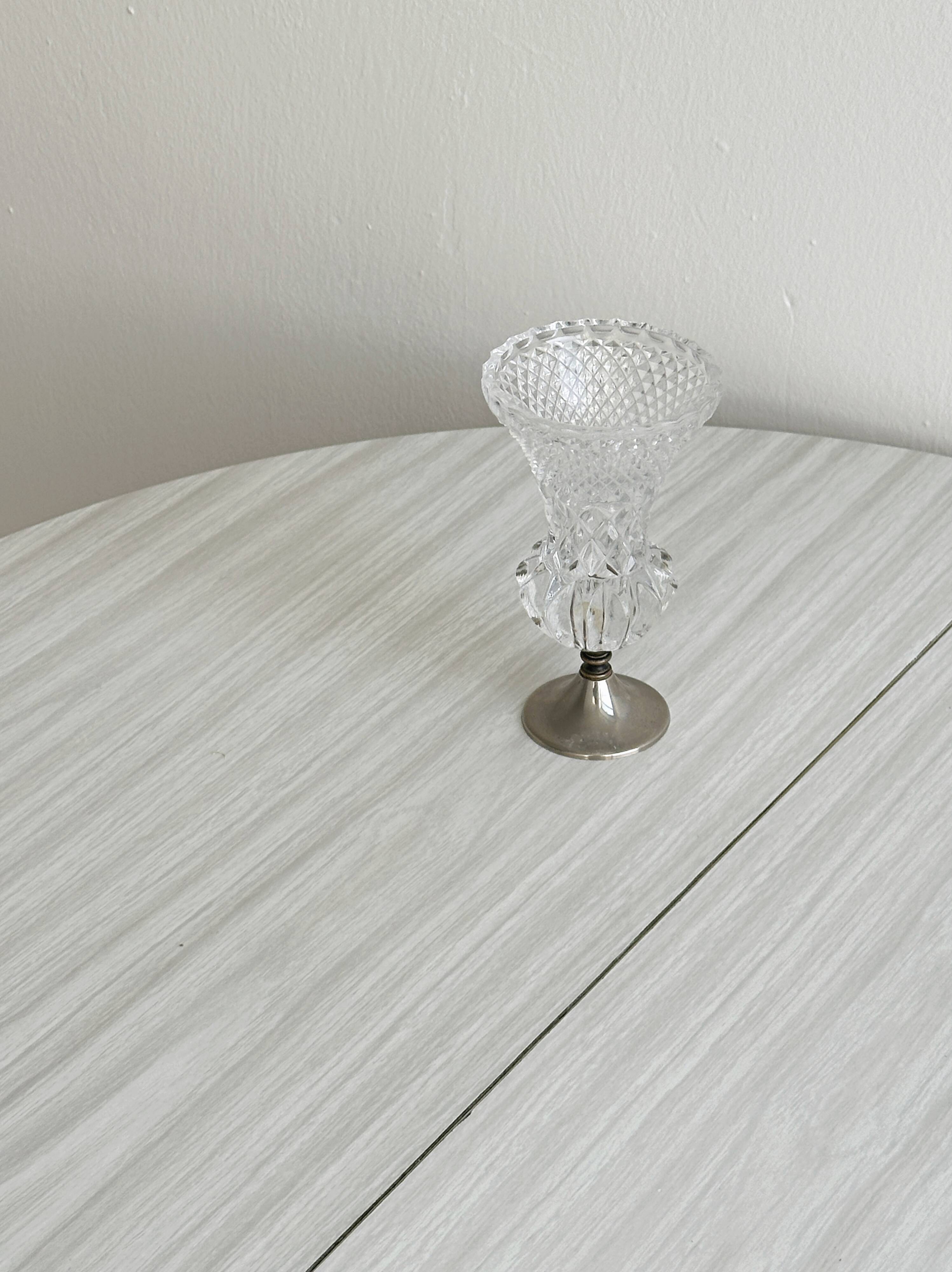 Small vase on a metal stand with thick glass.