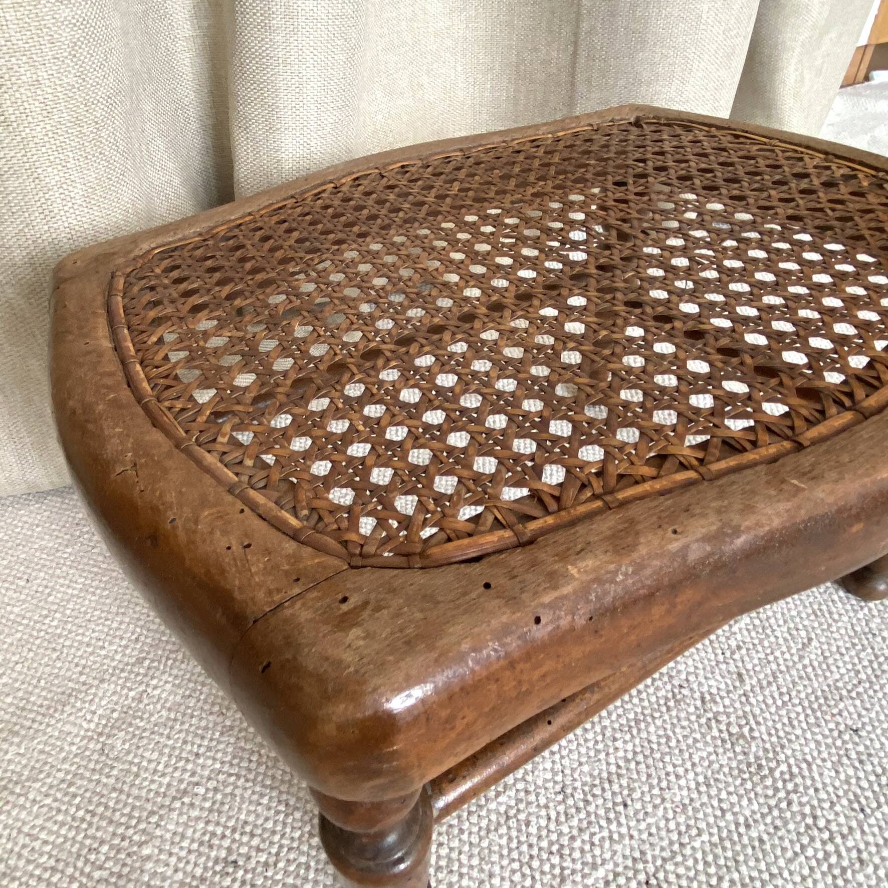 Low wooden stool with caning, footrest.