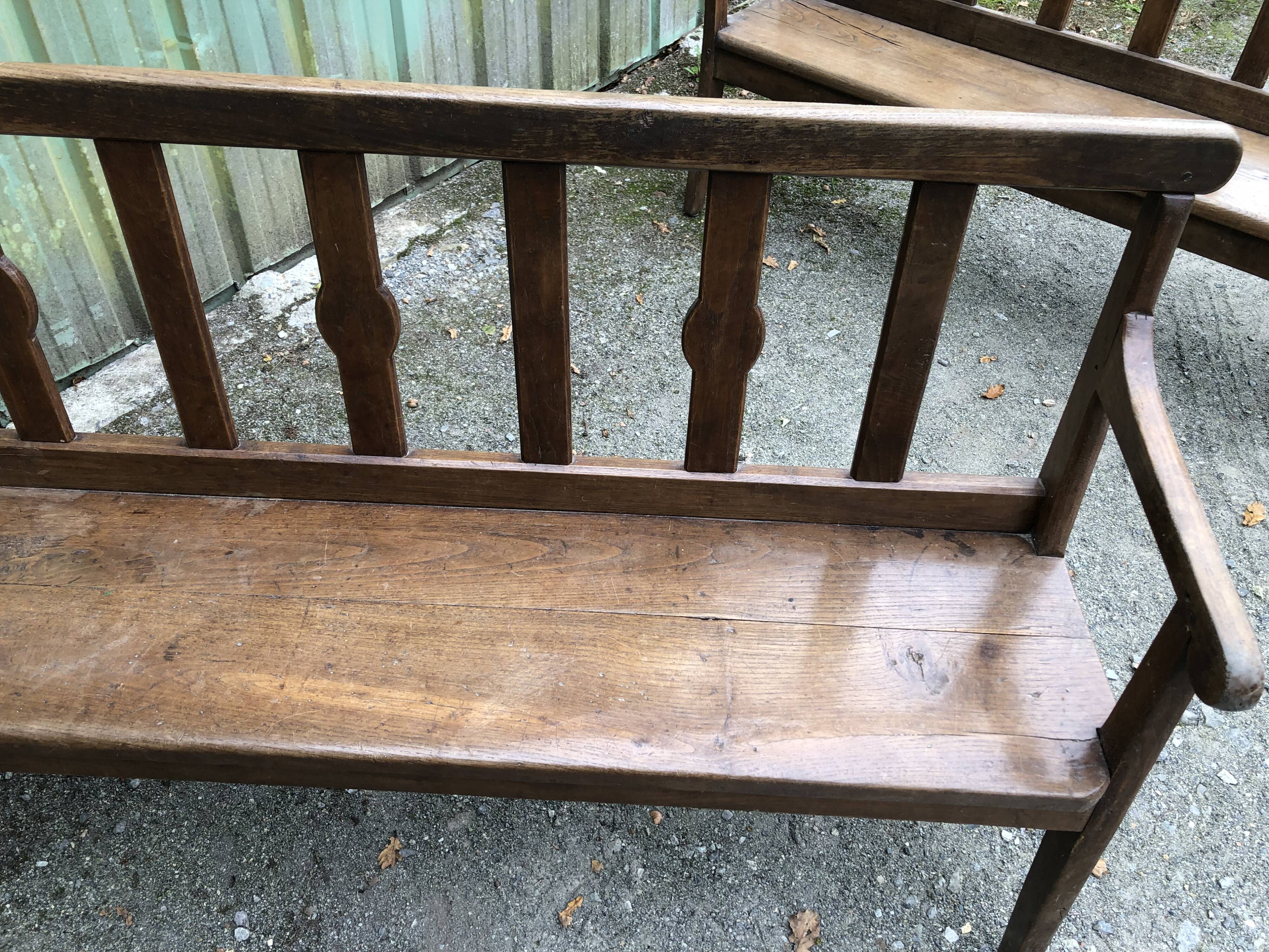 Duo of old solid oak benches with backs and armrests.