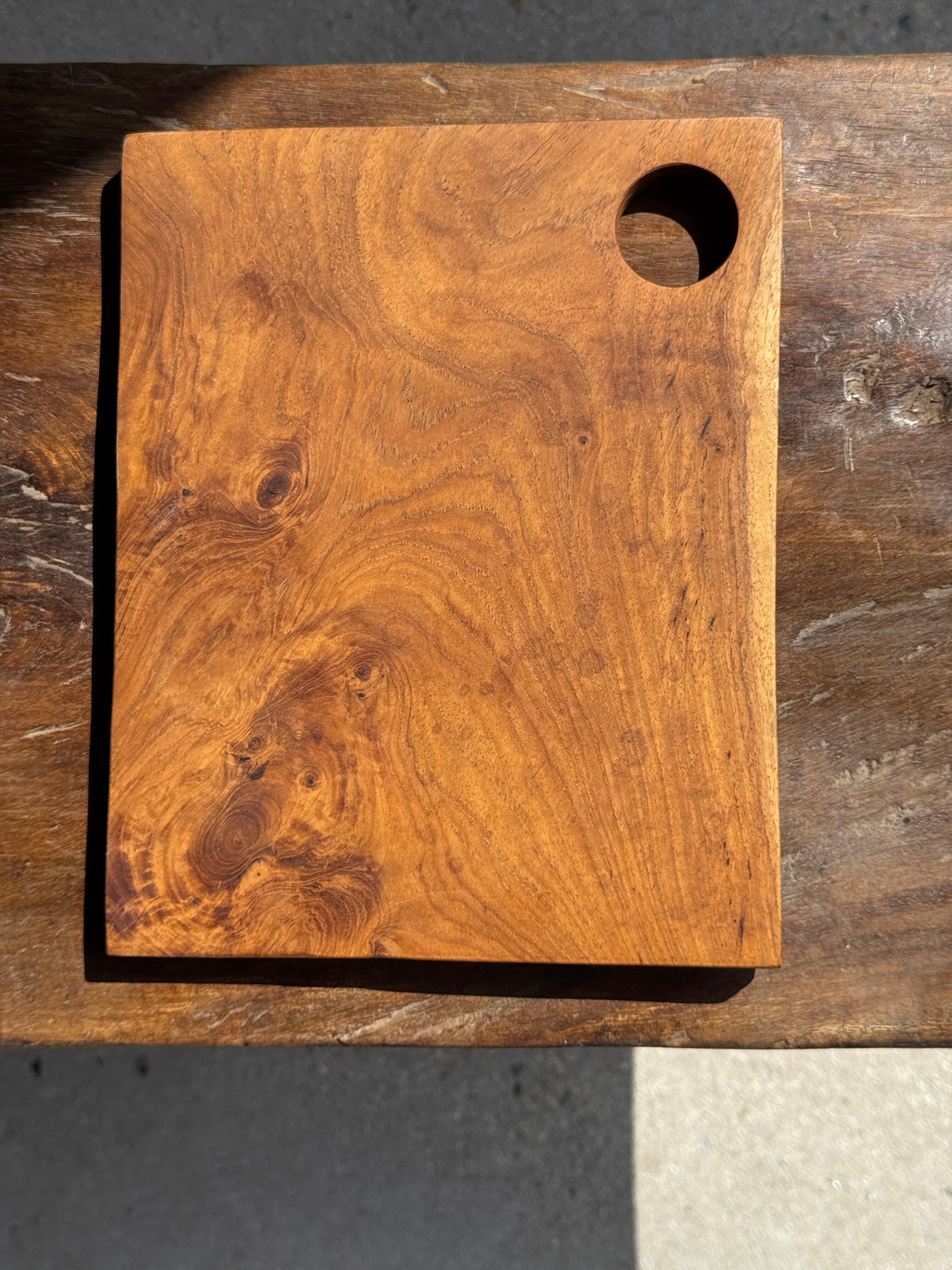 Small rectangular teak monoxyle cutting board with a circular handle.