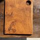 Small rectangular teak monoxyle cutting board with a circular handle.