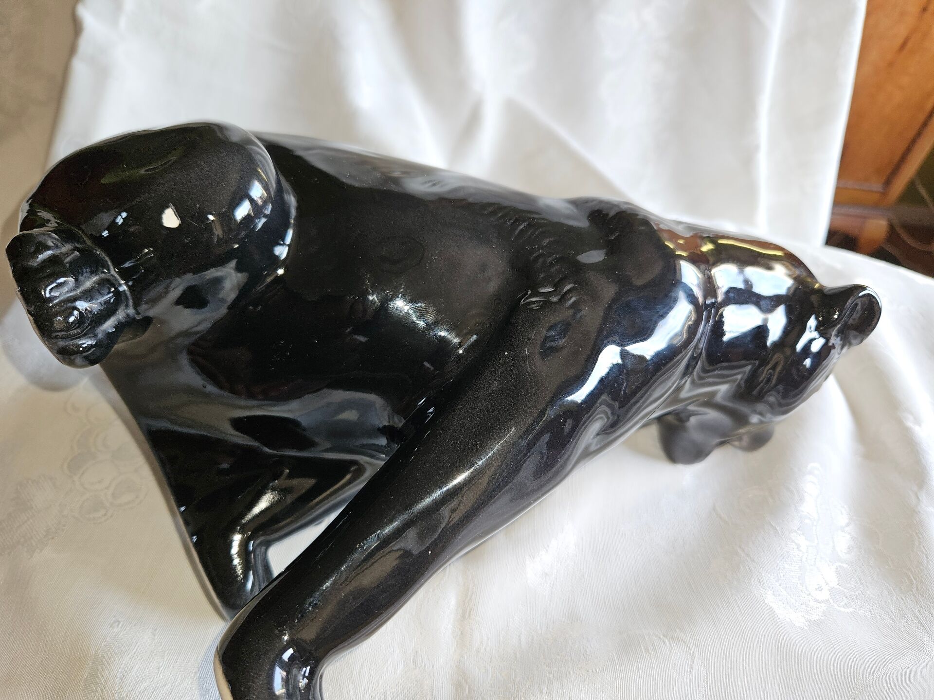 Statue of a roaring panther/leopard sitting in black glazed ceramic.
