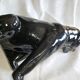 Statue of a roaring panther/leopard sitting in black glazed ceramic.
