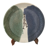 Glazed ceramic plate representation man between two lands unknown signature
