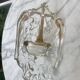 Old wall-mounted holy water font in moulded glass decorated with angels.