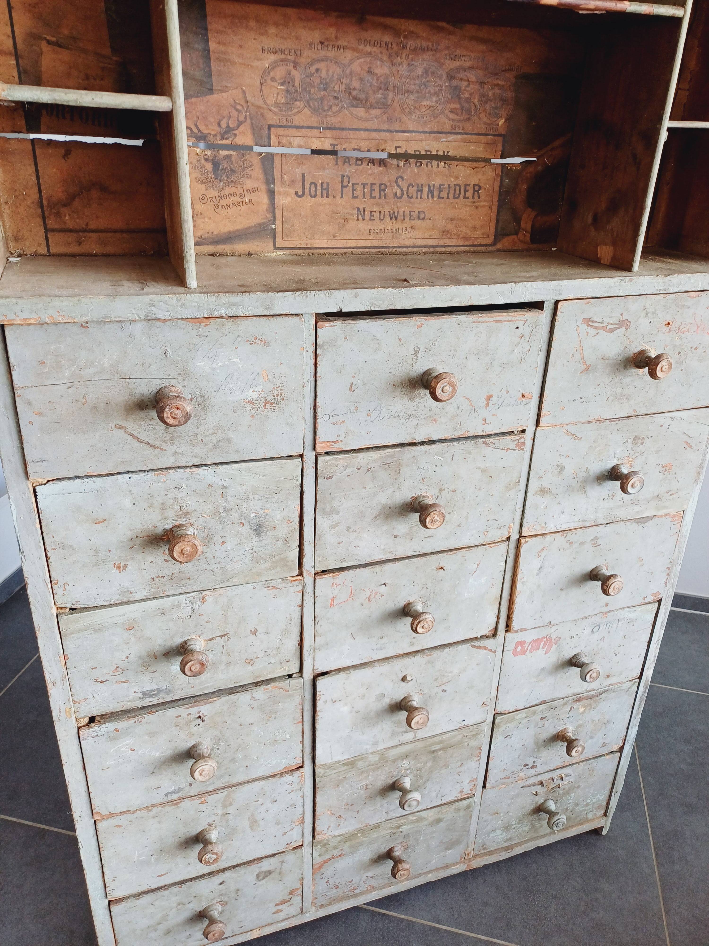 Craft cabinet with drawers with a very old tobacco advertisement in the background