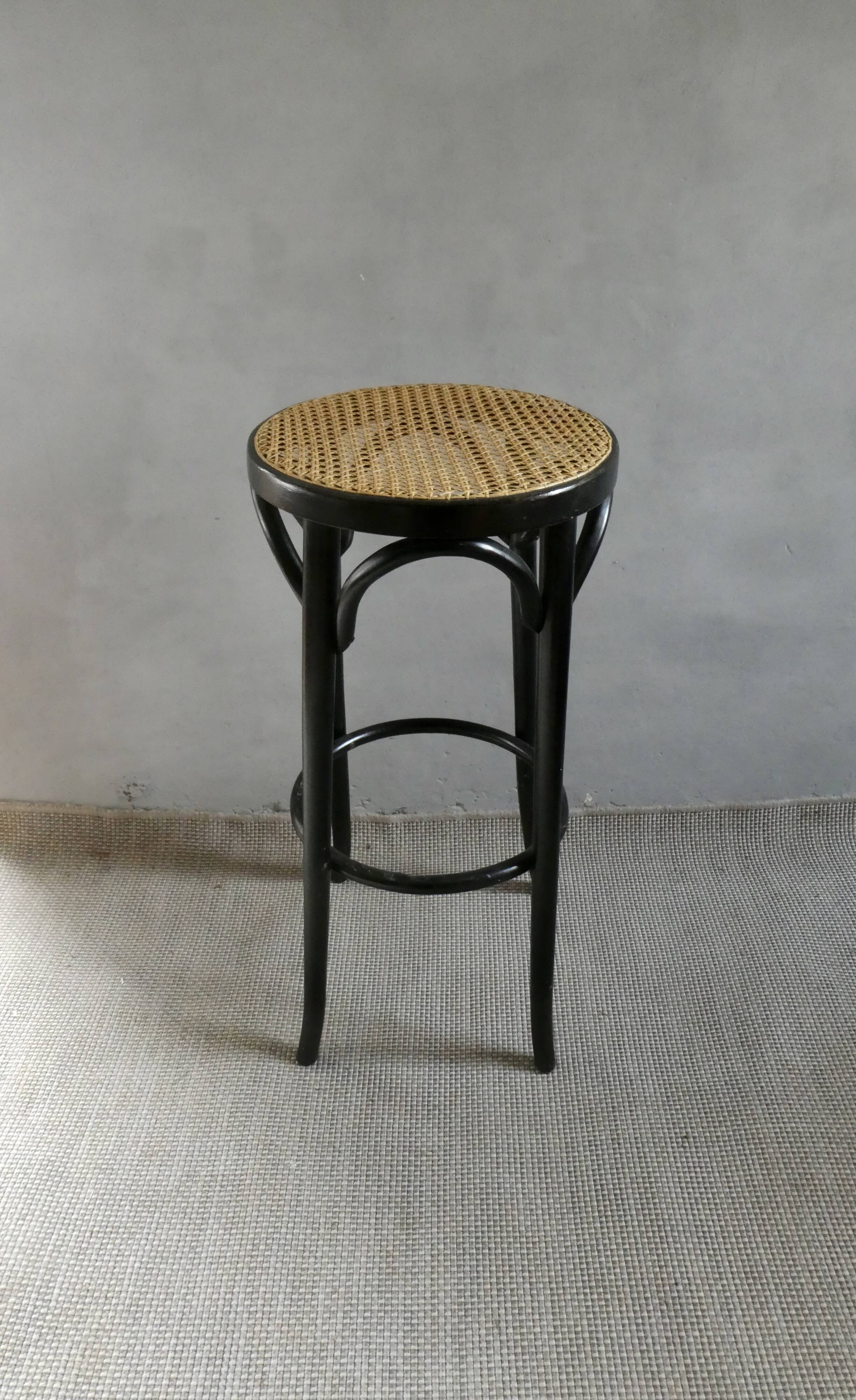 Curved wooden bar stool with a caned seat.