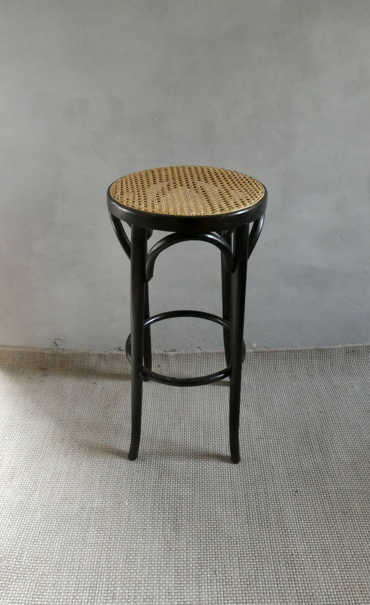 Curved wooden bar stool with a caned seat.