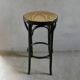 Curved wooden bar stool with a caned seat.