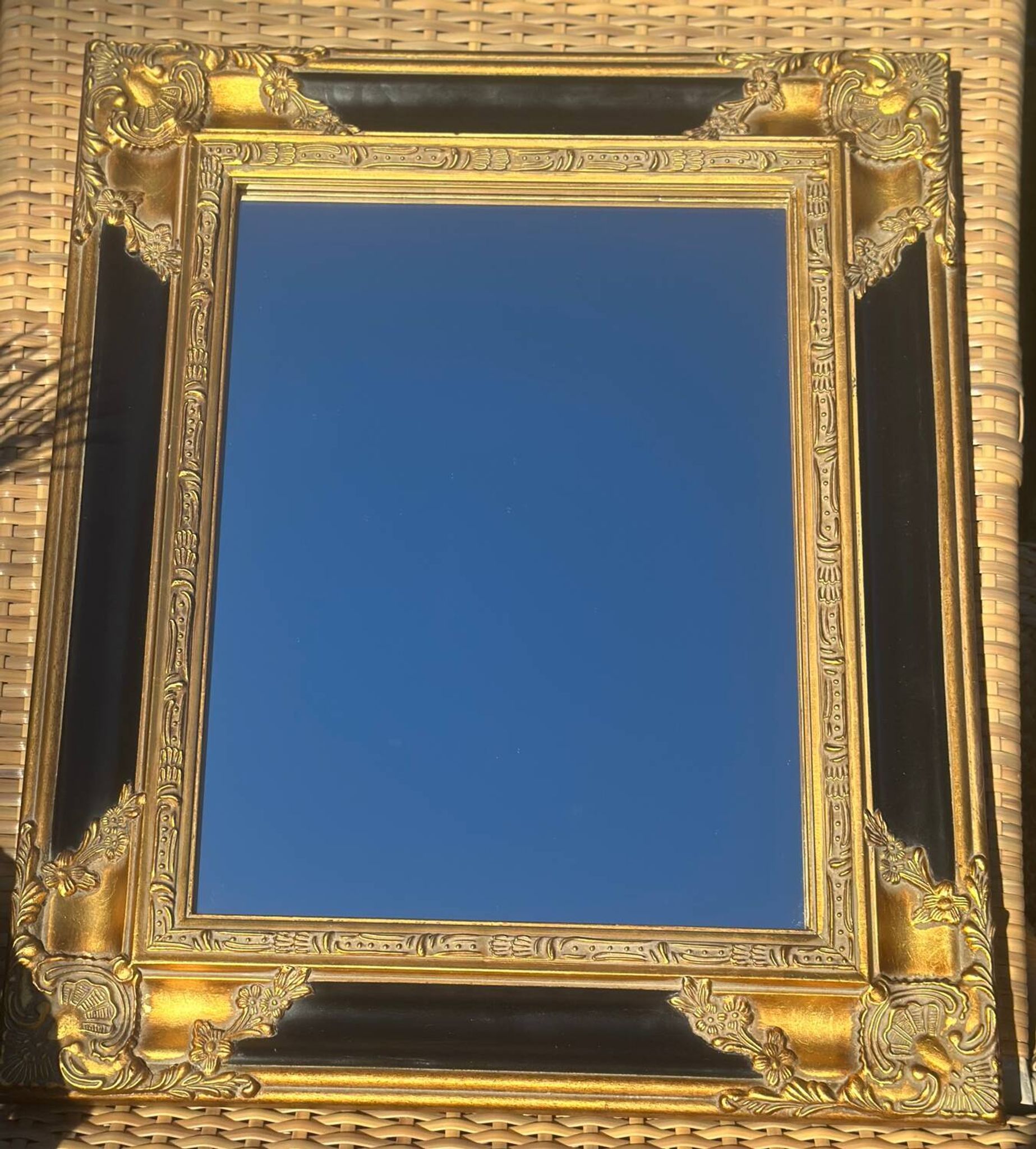 Miroir Baroque en bois doré sur fond noir.