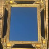 Baroque mirror in gilded wood on a black background.