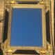 Baroque mirror in gilded wood on a black background.