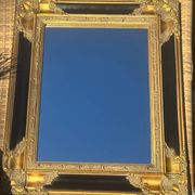 Miroir Baroque en bois doré sur fond noir.