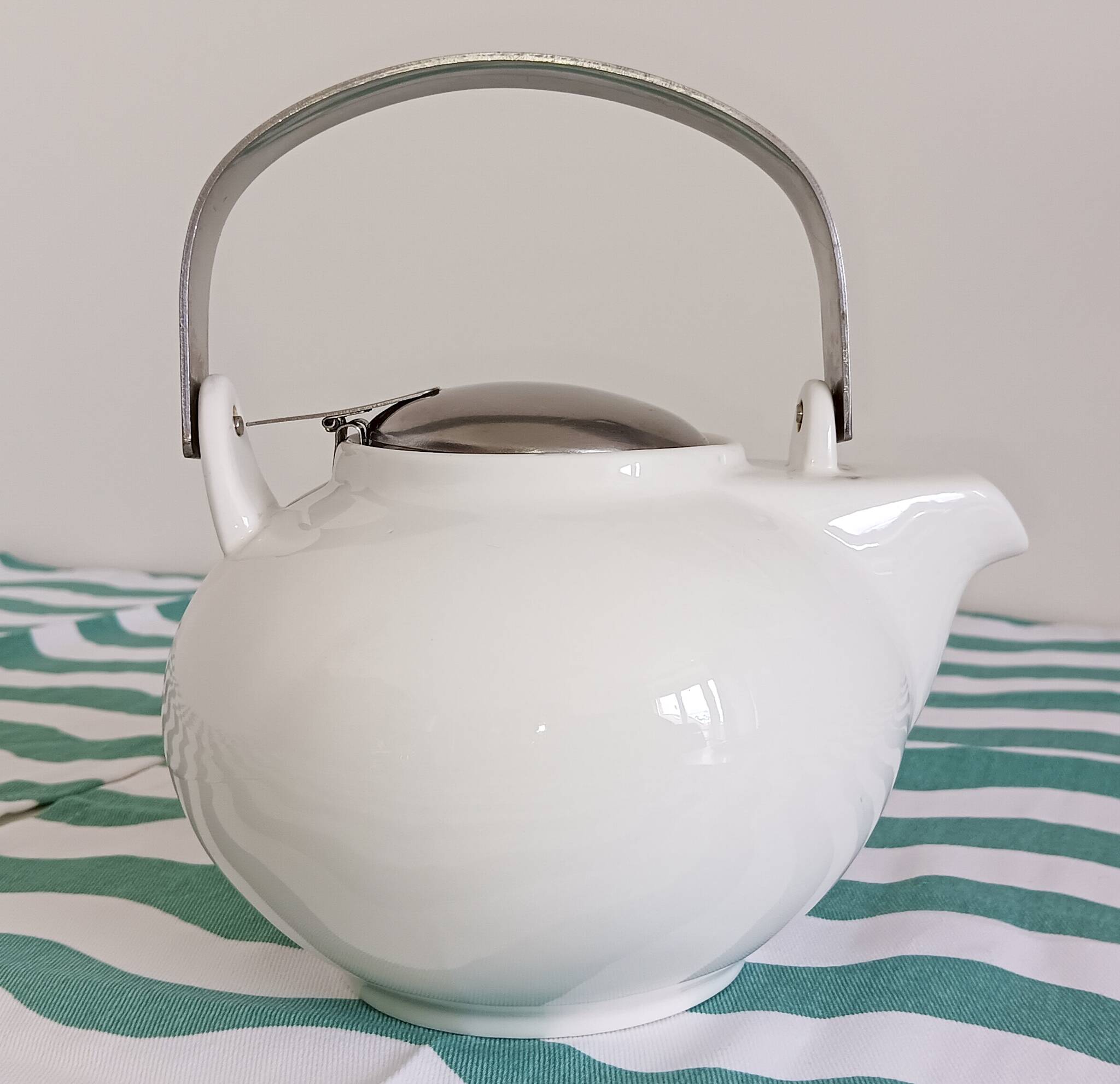 White porcelain teapot. Shiny stainless steel handle and lid